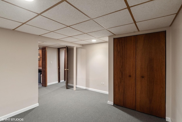 unfurnished bedroom featuring a closet, a drop ceiling, baseboards, and carpet floors