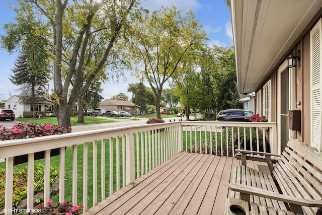 wooden deck featuring covered porch, a lawn, and a residential view