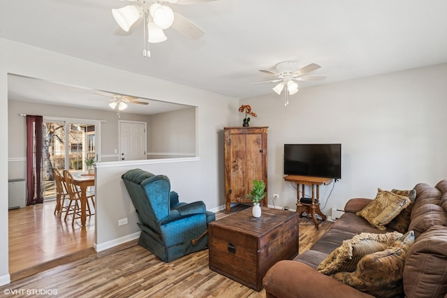 living room with baseboards, wood finished floors, ceiling fan, and a baseboard heating unit