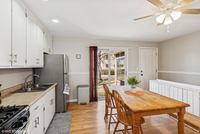 kitchen featuring a sink, light wood-style flooring, ceiling fan, and white cabinets