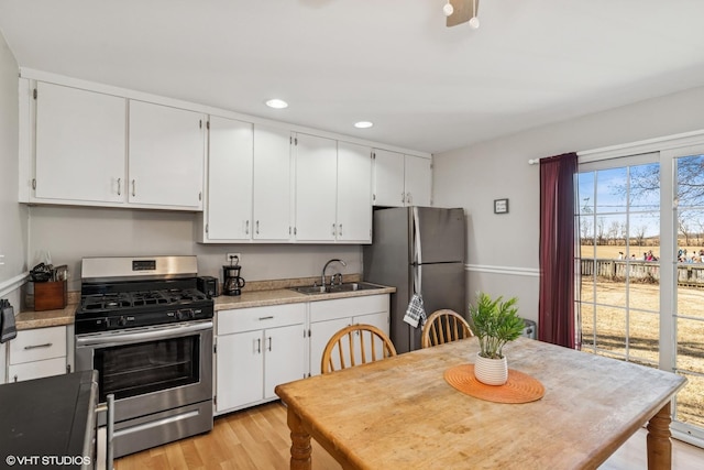 kitchen with a sink, stainless steel appliances, light wood-style floors, and white cabinets