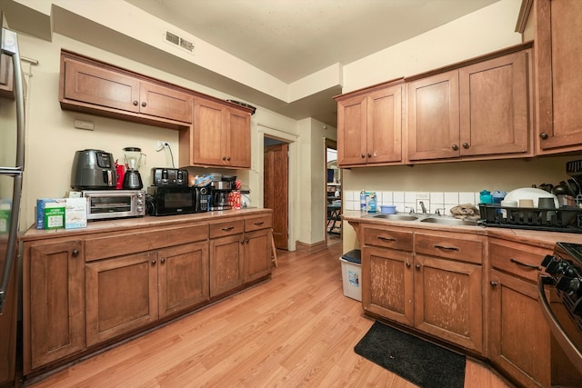 kitchen with light wood-type flooring, black appliances, and sink