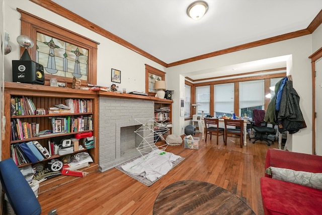 living room featuring wood-type flooring, ornamental molding, and a brick fireplace