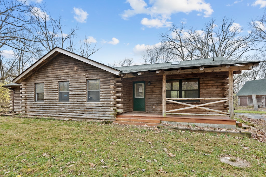 log cabin featuring covered porch and a front yard