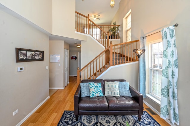 living room featuring ceiling fan, hardwood / wood-style floors, and a towering ceiling