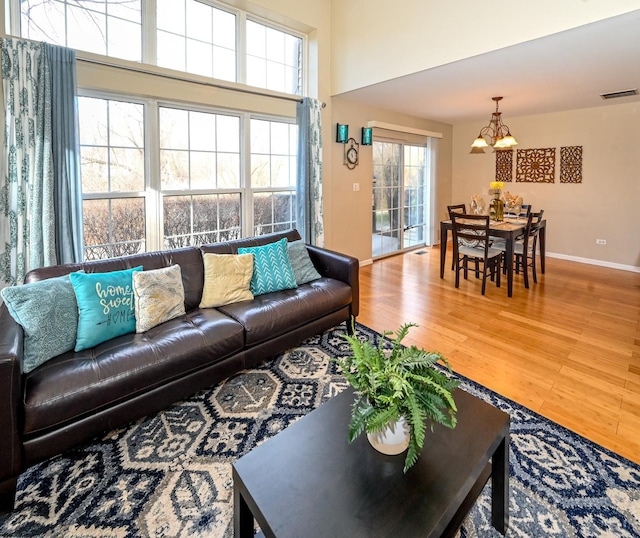 living room with plenty of natural light, wood-type flooring, and a notable chandelier