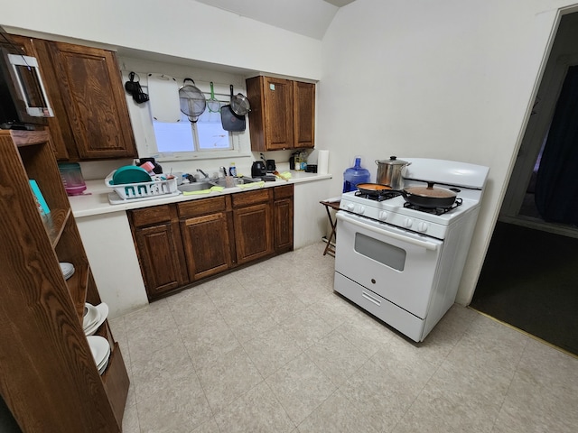 kitchen with dark brown cabinetry, sink, and gas range gas stove