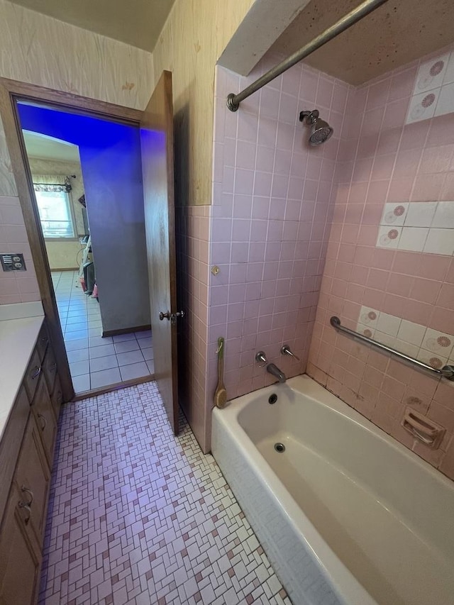 bathroom with tile patterned flooring, vanity, tiled shower / bath, and tile walls