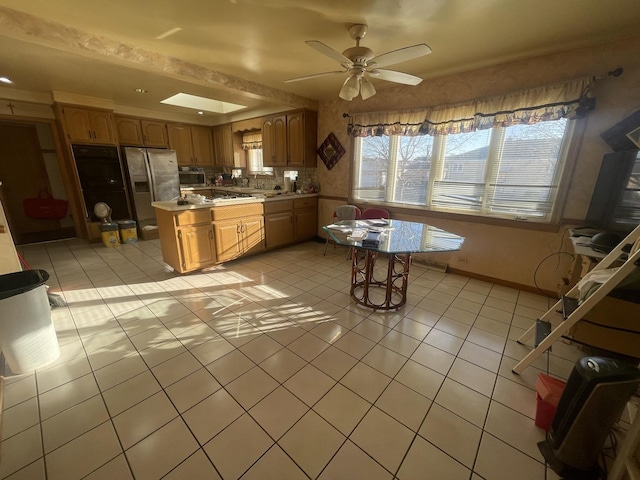 kitchen featuring ceiling fan, a center island, light tile patterned floors, and stainless steel appliances