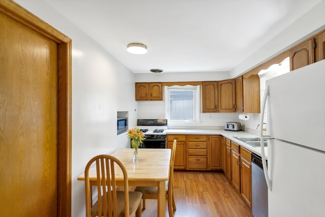 kitchen featuring sink, backsplash, appliances with stainless steel finishes, and light hardwood / wood-style flooring