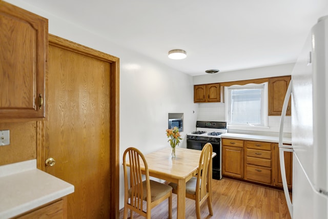 kitchen featuring white fridge, tasteful backsplash, light hardwood / wood-style floors, and range with gas cooktop