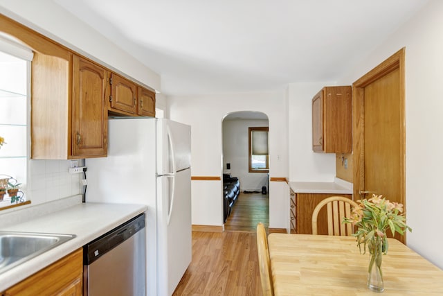 kitchen with decorative backsplash, sink, stainless steel dishwasher, and light wood-type flooring