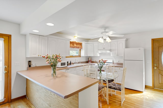 kitchen featuring light hardwood / wood-style floors, white cabinetry, white appliances, and kitchen peninsula