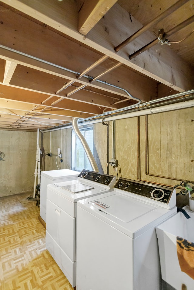 laundry area with washing machine and clothes dryer, sink, and light parquet flooring