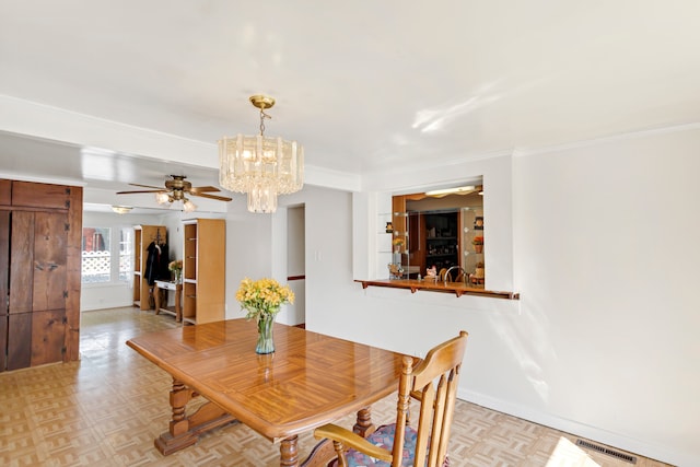 dining space with ceiling fan with notable chandelier, crown molding, and light parquet flooring