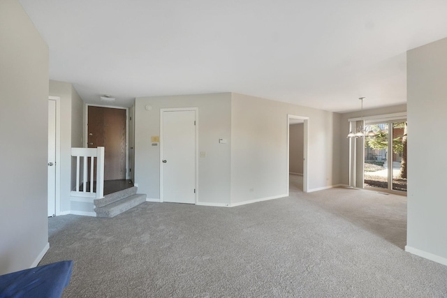 carpeted empty room with an inviting chandelier