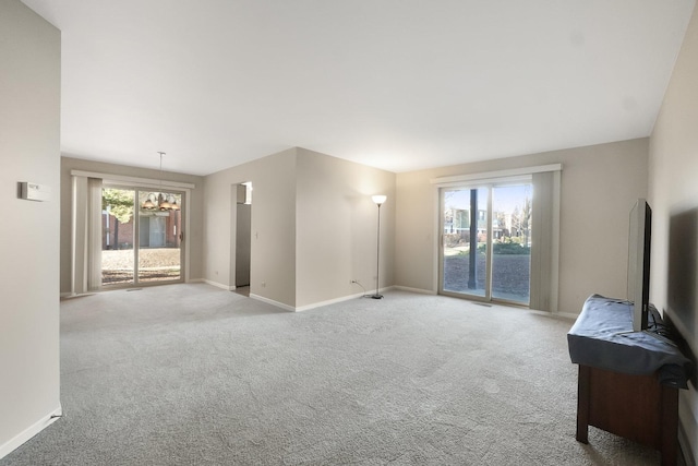 unfurnished living room featuring light carpet and plenty of natural light