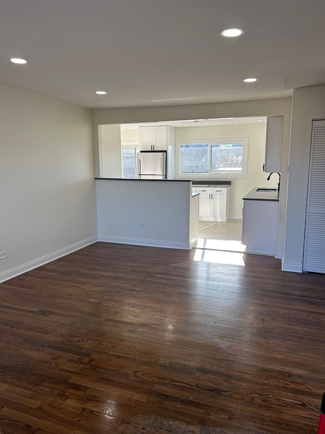 unfurnished living room featuring dark hardwood / wood-style flooring and sink