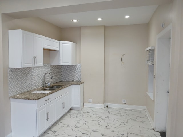 kitchen with backsplash, white cabinetry, dark stone counters, and sink