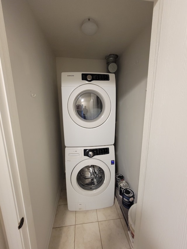 laundry room featuring light tile patterned flooring and stacked washer / dryer