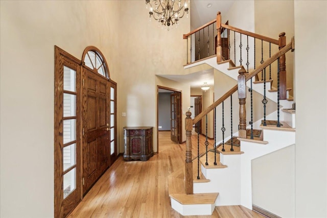 foyer entrance with hardwood / wood-style floors, a notable chandelier, and a high ceiling