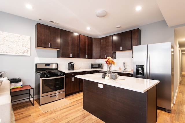 kitchen with backsplash, light hardwood / wood-style flooring, dark brown cabinets, and appliances with stainless steel finishes