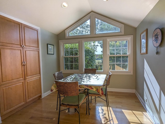 dining space with light hardwood / wood-style floors and vaulted ceiling