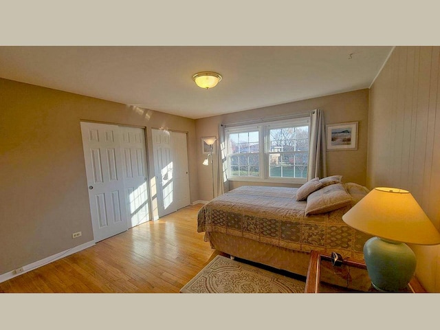 bedroom with light wood-type flooring and wooden walls