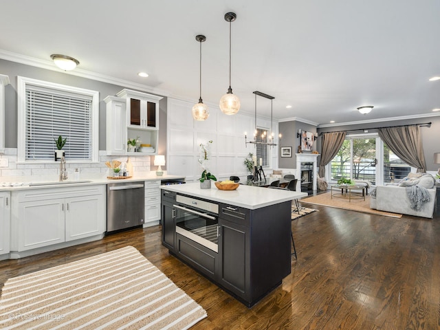 kitchen featuring appliances with stainless steel finishes, white cabinetry, hanging light fixtures, and sink