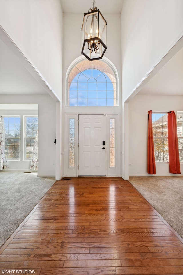 foyer featuring a chandelier, a towering ceiling, and carpet floors