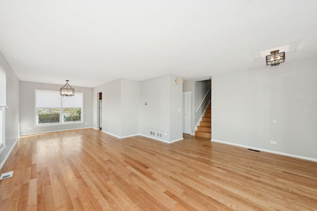 unfurnished living room with a chandelier and light wood-type flooring