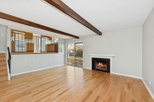 unfurnished living room featuring beamed ceiling and light wood-type flooring