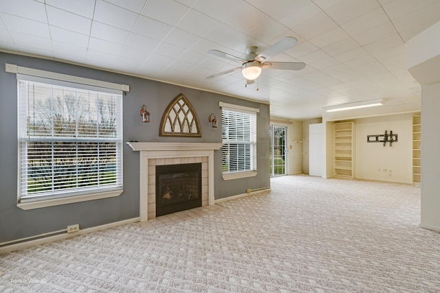 unfurnished living room featuring light carpet, a tile fireplace, a wealth of natural light, and ceiling fan