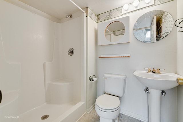 bathroom with walk in shower, sink, tile patterned flooring, and toilet