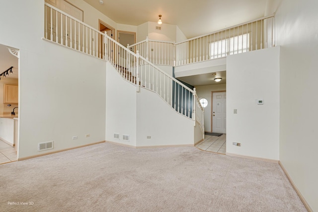 unfurnished living room with a towering ceiling and light colored carpet