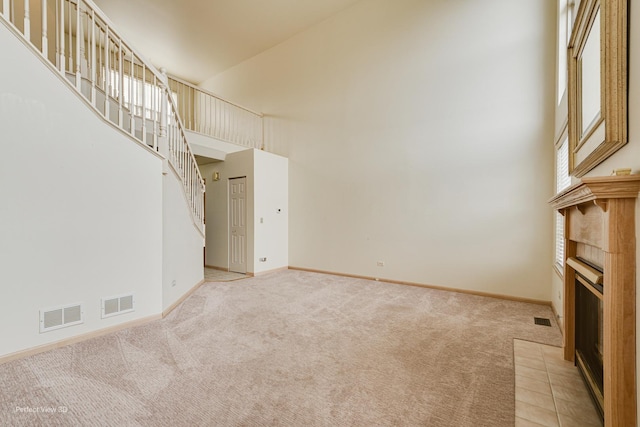 unfurnished living room with a fireplace, light carpet, and a high ceiling