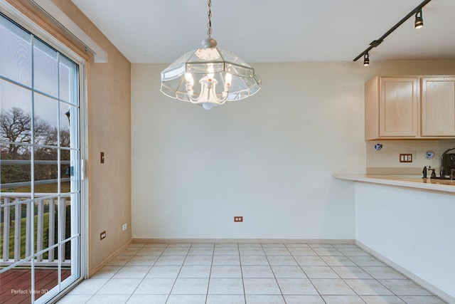 unfurnished dining area featuring track lighting, an inviting chandelier, and light tile patterned flooring