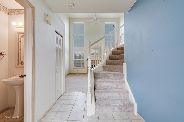 staircase featuring tile patterned floors, ceiling fan, and sink