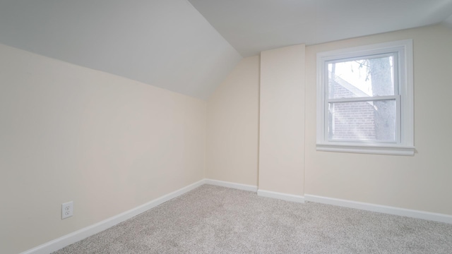 additional living space featuring light colored carpet and vaulted ceiling