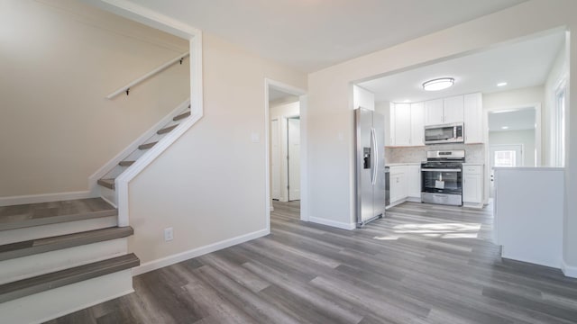 kitchen featuring white cabinets, wood-type flooring, backsplash, and appliances with stainless steel finishes