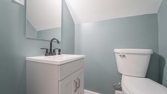 bathroom with vanity, toilet, and lofted ceiling