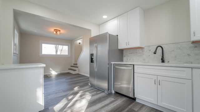 kitchen featuring appliances with stainless steel finishes, tasteful backsplash, sink, white cabinets, and dark hardwood / wood-style floors