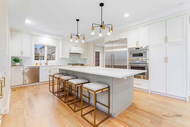 kitchen with stainless steel appliances, a kitchen breakfast bar, a center island, and white cabinets