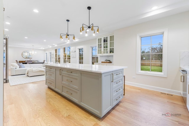 kitchen with gray cabinets, a kitchen island, a chandelier, and decorative light fixtures