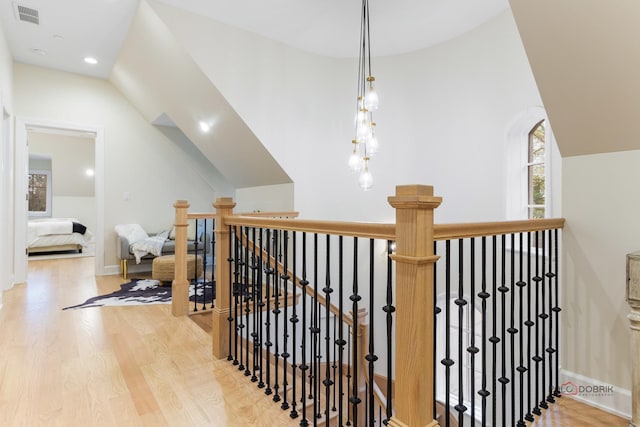 hall with wood-type flooring and vaulted ceiling