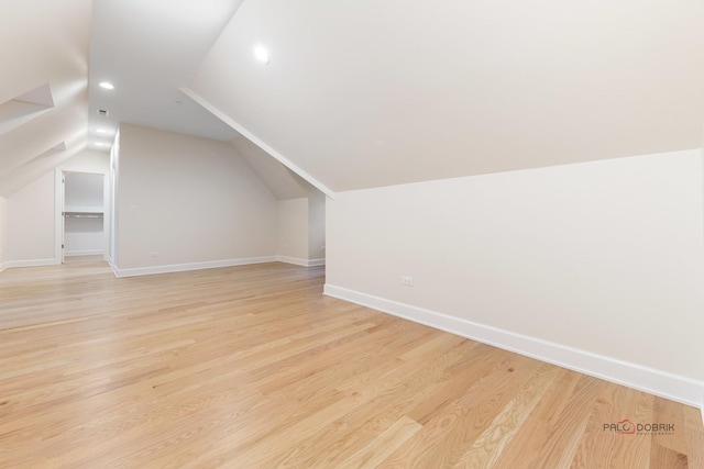 additional living space featuring vaulted ceiling and light wood-type flooring