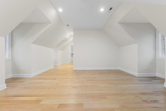 additional living space featuring lofted ceiling and light hardwood / wood-style floors