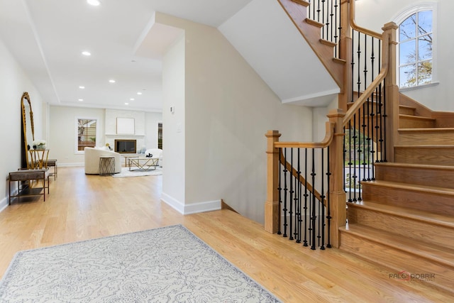 staircase with a fireplace and hardwood / wood-style floors