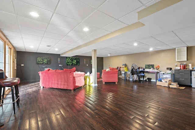 living room featuring a paneled ceiling and dark wood-type flooring