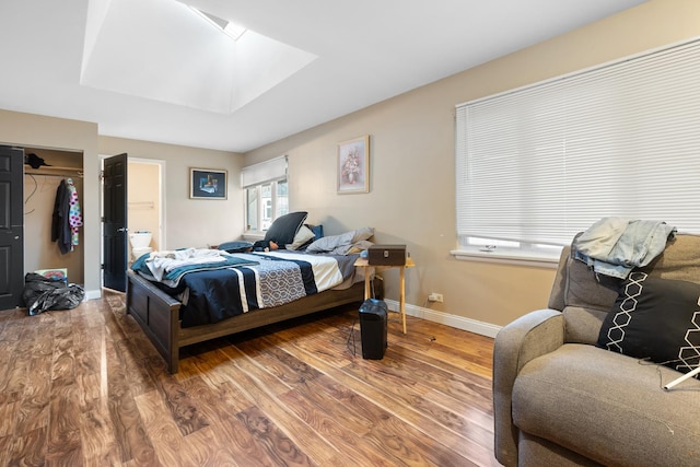 bedroom with a closet, hardwood / wood-style flooring, and a skylight